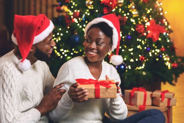 Caring afro man surprising his girlfriend with Christmas gift
