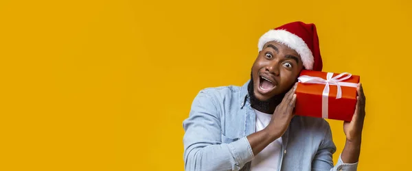 Hombre negro divertido sosteniendo la caja de regalo de Navidad, preguntarse qué hay dentro — Foto de Stock