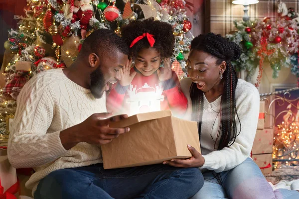 Família negra excitada de três abertura brilhante caixa de presente de Natal — Fotografia de Stock
