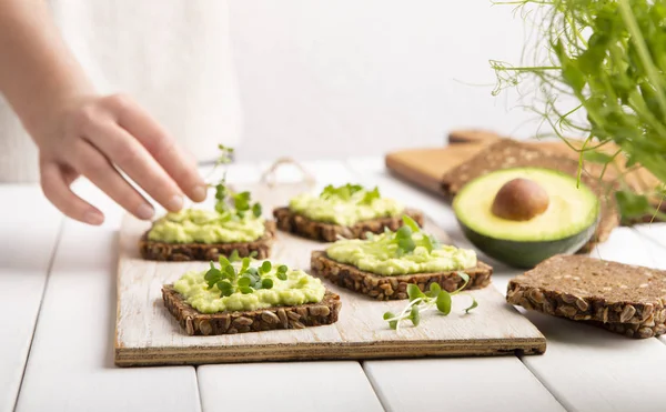 Girl preparing sandwiches with avocado spread and microgreen — Stock Photo, Image