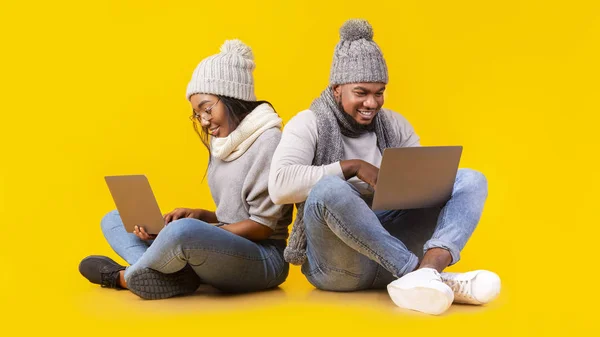 Amistosa pareja africana usando computadoras portátiles, sentada en el suelo — Foto de Stock