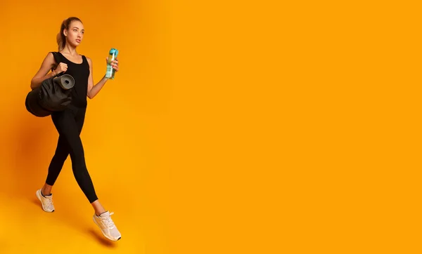 Fitness lány megy tornaterem szállító táska át sárga háttér — Stock Fotó