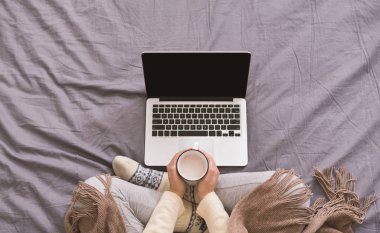 Kadın aromatik kahve içiyor ve dizüstü bilgisayar izliyor.