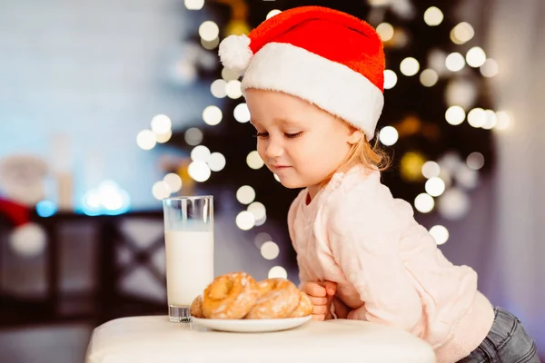 Linda niña mirando golosinas para Santa cerca del árbol de Navidad —  Fotos de Stock