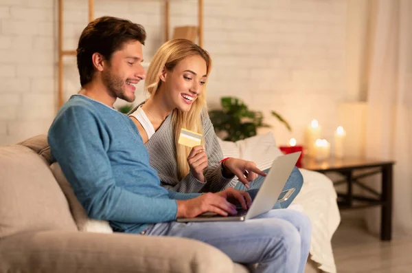 Manželé drží notebook a kreditní karty sedí na gauči vnitřní — Stock fotografie