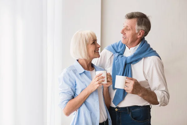 Morning coffee. Senior couple drinking tea near window