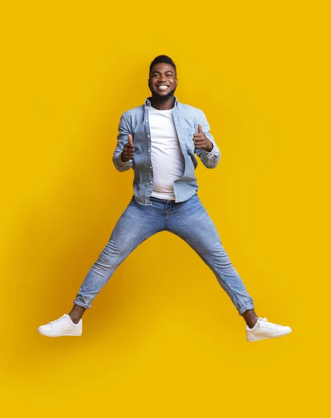 Homem africano feliz pulando no ar com os polegares para cima — Fotografia de Stock