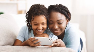 Siyahi kız ve anne iPhone 'u en fazla 11 profesyonel olarak tutuyor.
