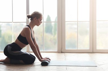 Yoga yaptıktan sonra atölyede yoga minderi çeviren sportif kız.