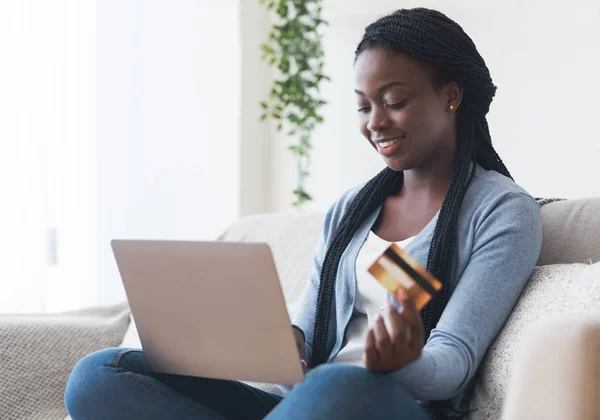 Schwarzes Mädchen mit Laptop und Kreditkarte Dinge online kaufen — Stockfoto