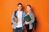 Nadšený studentský pár s batohy a knihami