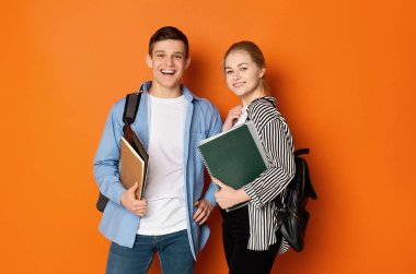 Excited student couple with backpacks and books clipart