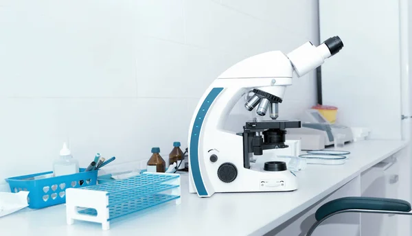 Fechar o microscópio na mesa com tubos de ensaio e outros equipamentos — Fotografia de Stock