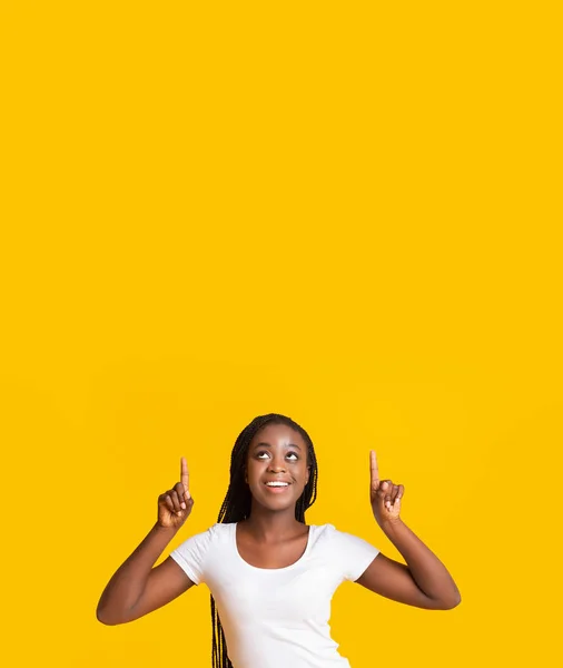 Amazed smiling afro girl pointing up at empty space — Stock Photo, Image