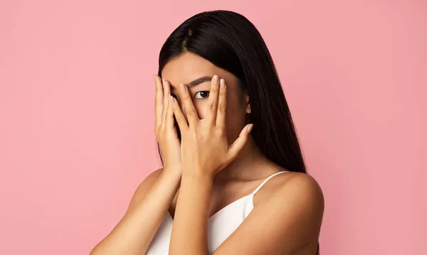 Verlegen aziatische meisje sluiten gezicht met handen, kijken door vingers — Stockfoto