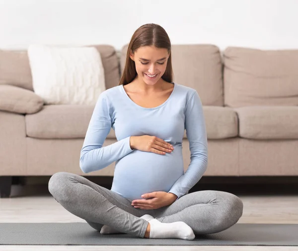 Vonzó terhes nő fogdossa a hasát és mosolyog — Stock Fotó