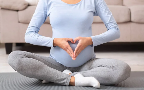 Close-up da barriga com as mãos fazendo uma forma de coração — Fotografia de Stock