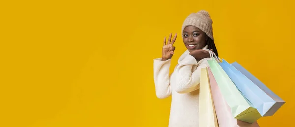 Feliz chica de invierno con bolsas de compras que muestran bien —  Fotos de Stock