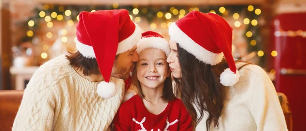 Genç anne ve baba küçük kızlarını öpüyor.