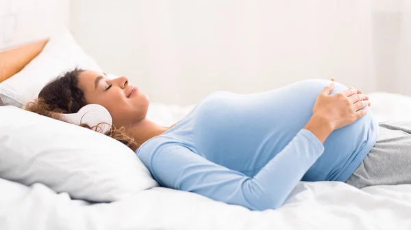 Rahatlamış hamile kadın kulaklıkla müzik dinliyor. — Stok fotoğraf