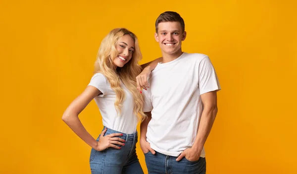 Усміхнена молода пара позує в студії на жовтому фоні — стокове фото