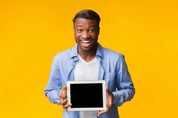 Hombre excitado sosteniendo la tableta con pantalla vacía de pie en el estudio —  Fotos de Stock