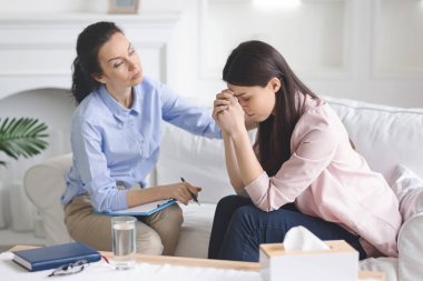 Terapist depresyondaki ağlayan kadın hastasını rahatlatıyor.