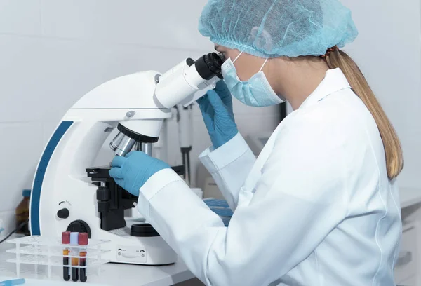 Científica joven estudiando nueva sustancia o virus en el microscopio —  Fotos de Stock