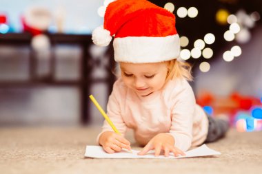 Odaklanmış küçük kız Noel Baba 'ya mektup yazıyor.