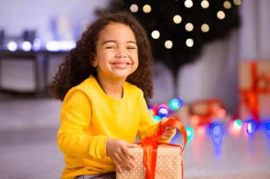 Neşeli siyah kız Noel arifesinde hediyeleri açıyor.