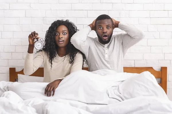 Black couple missed alarm clock ringing, sitting shocked in bed — Stock Photo, Image