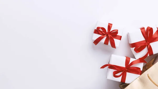 Torba pełna prezentów świątecznych zawinięta w czerwoną wstążkę — Zdjęcie stockowe