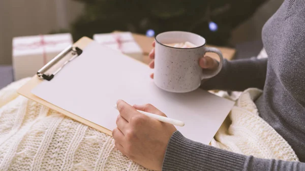 Female writing her Christmas wishes on white clipboard — Stock Photo, Image