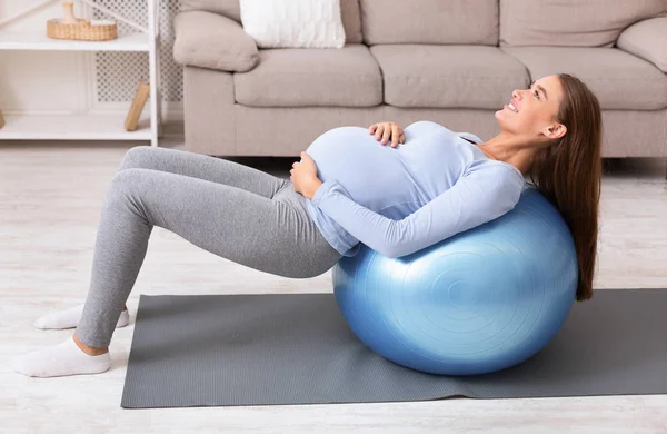 Gravid flicka tränar med fitness boll hemma — Stockfoto