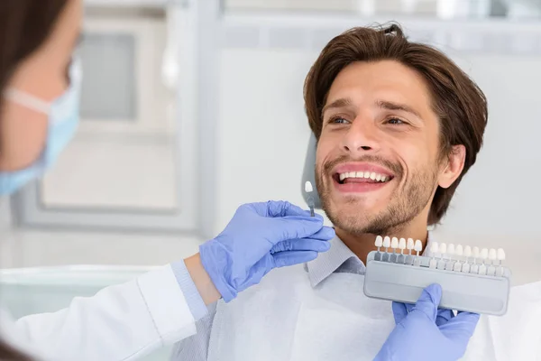 Comprobación del dentista en el color de los dientes del paciente masculino — Foto de Stock