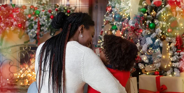 Afro mãe abraçando com sua filhinha na sala de estar decorada — Fotografia de Stock