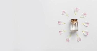 Beyaz üzerine pembe taç yaprakları sarılmış gerekli yağ şişesi.