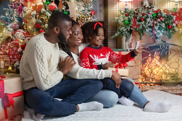 Menina preta tomando selfie com os pais perto da árvore de Natal — Fotografia de Stock