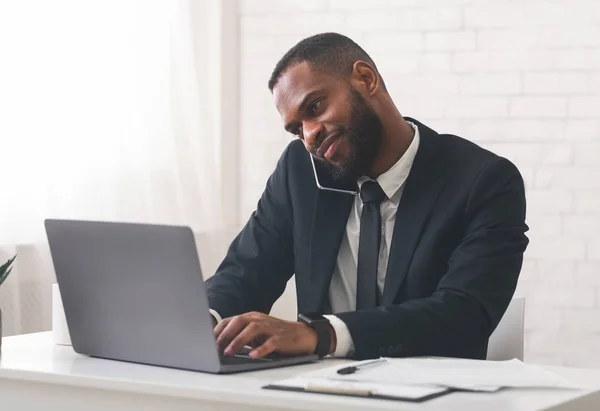 Hombre de negocios alegre hablando con el cliente por teléfono y utilizando la computadora — Foto de Stock