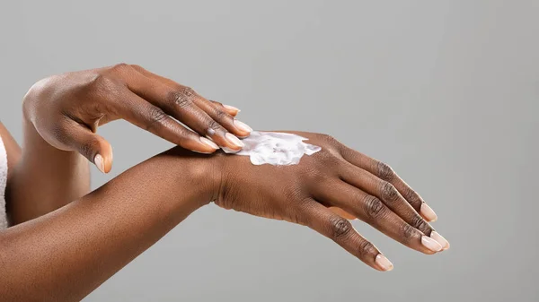Mujer negra aplicando loción corporal a sus manos —  Fotos de Stock