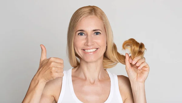Έντονη γυναίκα που δείχνει τα υγιή μαλλιά και τον αντίχειρά της επάνω — Φωτογραφία Αρχείου