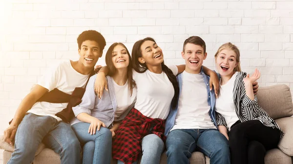 Adolescentes felizes abraçando, sentados no sofá e sorrindo — Fotografia de Stock