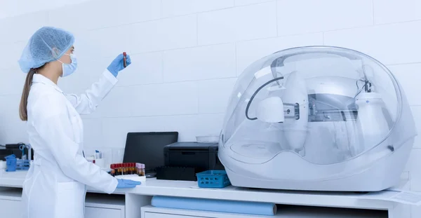 Donna in abiti medici guardando il sangue in provetta — Foto Stock