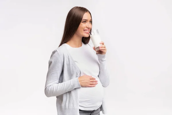 孕妇站在灰蒙蒙的背景下喝牛奶 — 图库照片