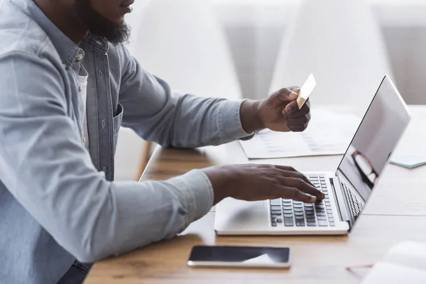 Negro hombre de negocios pagando sus facturas en línea con el ordenador portátil y tarjeta de crédito —  Fotos de Stock