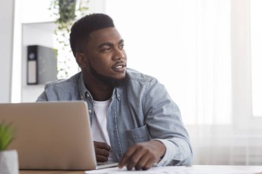 Modern ofiste işyerinde oturan dalgın afro iş adamının portresi.