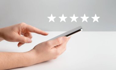 Gri üzerinden cep telefonundaki mobil uygulamayı değerlendiren kadın.