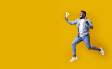 Siyah adam elinde parayla zıplıyor, büyük satışlar için heyecanlanıyor.