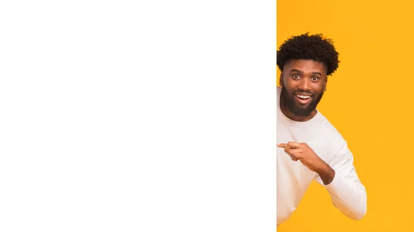 Cheerful black man pointing at big empty white board — Stock Photo, Image