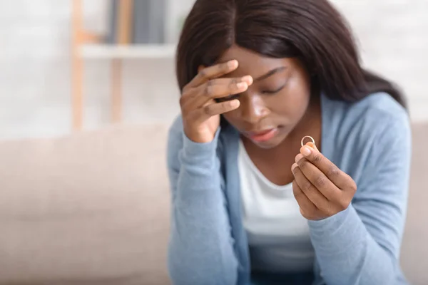 Deprimida afro mulher segurando anel de casamento de ouro, triste sobre o divórcio — Fotografia de Stock